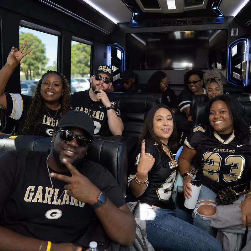 Group boarding a white charter bus for Sporting Event Transportation transportation in Garland